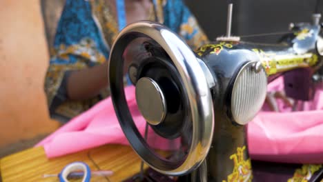 Close-up-slow-motion-shot-of-an-African-womans-hands-spinning-the-wheel-on-a-manual-operating-tailoring-machine
