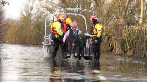 Reino-Unido-Febrero-De-2014:-Los-Bomberos-Ayudan-A-Los-Residentes-A-Desembarcar-De-Un-Barco-Que-Se-Utiliza-Como-Ferry-A-La-Aldea-De-Muchelney,-Aislada-Por-Las-Inundaciones-En-Los-Niveles-De-Somerset