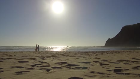 Pareja-Caminando-Por-La-Playa-Con-Un-Cielo-Limpio-Por-La-Tarde-Y-Mucha-Tranquilidad-En-La-Playa-Más-Hermosa-De-Portugal,-Odeceixe