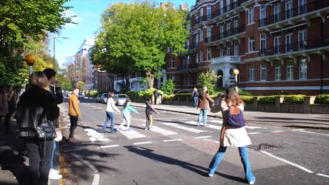 Touristen-Fotografieren,-Wie-Menschen-über-Den-Fußgängerüberweg-In-Der-Berühmten-Abbey-Road-Gehen,-Wie-Es-Die-Beatles-In-Den-1960er-Jahren-Auf-Der-Abbey-Road-Taten