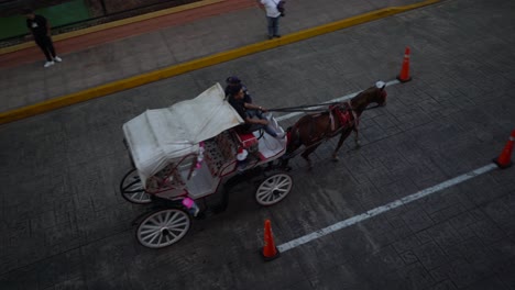 Overhead-shot-of-horse-drawn-carriage-trotting-down-the-street-in-Merida,-Yucatan,-Mexico