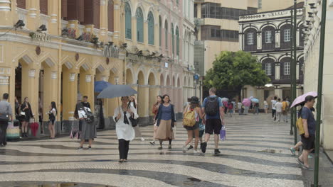 Senado-Square-with-colorfully-painted-buildings-and-tourists-passing-by-on-a-cloudy-overcast-day-in-Macau,-Macau-SAR,-China