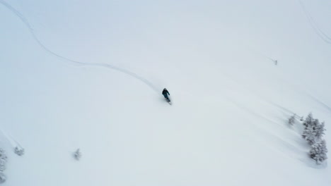 Vista-Aérea-Rastreando-A-Un-Snowboarder-Fuera-De-Pista-En-Nieve-Fresca
