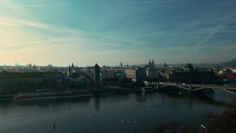 drone-flight-over-prague-vlatava-river-showing-bridges-castle-park-and-buildings-winter-sunshine