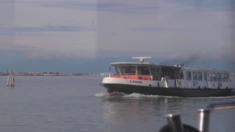 Slow-motion-shot-of-ferry-carrying-passengers-passing-by-off-the-coast-of-Venice,-Italy