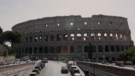 Static-wide-shot-for-The-Colosseum-of-Rome-with-people-and-cars-driving-in-front-of-it