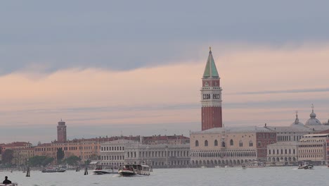 Flugzeug-überquert-Den-Sonnenuntergangshimmel-über-Dem-Wasser,-Den-Bootsverkehr-Im-Canal-Grande-In-Venedig