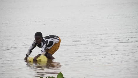 Una-Joven-Africana-Recogiendo-Agua-De-Un-Bidón-Amarillo-En-El-Lago-Victoria