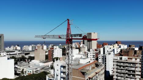 Aerial-view-of-the-city-Montevideo-Uruguay,-with-buildings,-a-crane-building,-the-sea-and-the-clear-sky-in-the-background