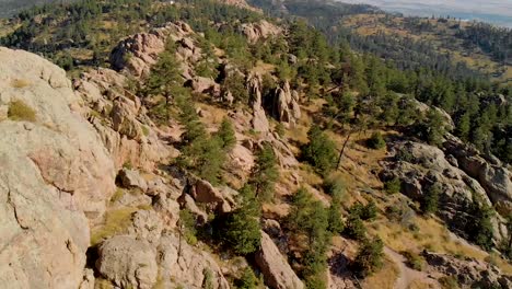Drone-shot-of-mountainous-terrain,-hikers-and-cityscape-in-the-distance