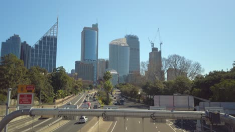 Footage-of-a-busy-Sydney-city-highway-from-a-bridge-with-office-building-on-a-clear-sunny-day,-NSW-Australia