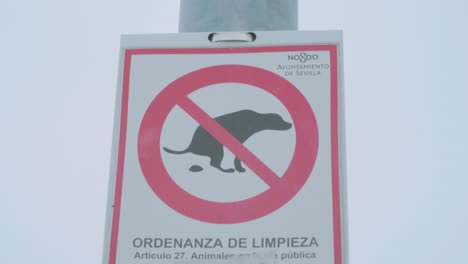 Sign-ordering-dog-owners-to-clean-up-dog-poop-in-Seville,-Spain,-Zoom-In