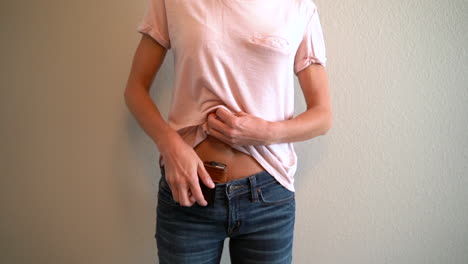 Slow-motion-of-a-woman-puling-up-her-shirt-and-removing-her-concealed-and-holster-gun-from-her-waistline