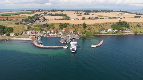 Aerial-view-paning-sideways-of-the-ferry-Uraniborg-going-into-the-harbor-of-Bäckviken-on-the-island-of-Ven-in-southern-Sweden,-arriving-from-Landskrona