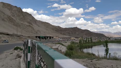 the-clean-and-serene-roads-of-leh-with-lake-blue-sky-white-clouds-and-car-and-vehicle-moving-on-the-roads-in-between-mountains