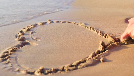 Ein-Herz-Wird-Von-Einem-Mädchen-In-Den-Sand-Eines-Strandes-Gezeichnet