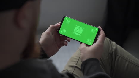 Mockup.-Man-holding-smartphone-with-horizontal-green-screen-chroma,-swiping-and-scrolling.