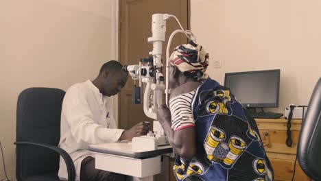 Afrikanischer-Arzt-überprüft-Die-Sehkraft-Des-Patienten-In-Der-Augenklinik-Und-Der-Arzt-Bewegt-Geräte-Und-Stellt-Den-Kopf-Des-Patienten-An-Die-Richtige-Stelle,-Um-Anpassungen-Vorzunehmen