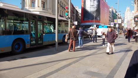 Tráfico-En-Gran-Vía-En-El-Centro-De-La-Ciudad-De-Madrid,-Autobuses,-Automóviles-Y-Peatones-Pasan