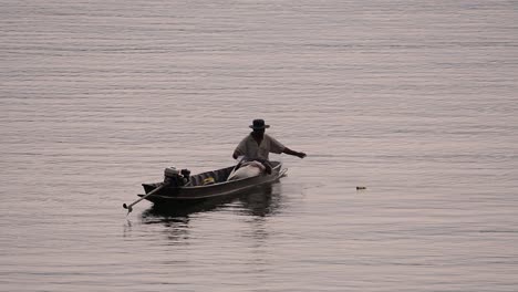 Fisherman-silhouetting-as-he-is-casting-and-drawing-his-net-in-the-River-before-dark,-in-slow-motion