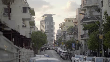 Calle-Tel-Aviv-En-El-Centro-De-La-Ciudad-Con-Edificio-De-Negocios-En-El-Fondo-Y-Autos-Estacionados