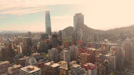 Aerial-over-concrete-jungle-flying-towards-tall-skyscrapers-on-a-sunny-afternoon,-Santiago-de-Chile-4K