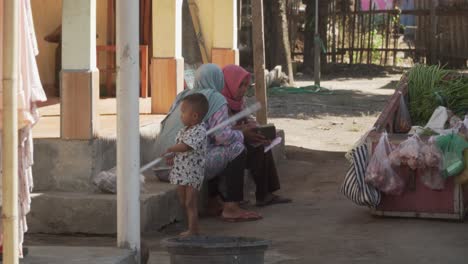 Kleines-Kind,-Das-Neben-Zwei-Muslimischen-Frauen-In-Einem-Kleinen-Dorf-In-Indonesien-Spielt