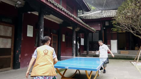 Chengdu,-China---July-2019-:-Man-and-woman-playing-ping-pong-in-the-courtyard-of-Wenshu-Monastery-in-Chengdu,-Sichuan-Province