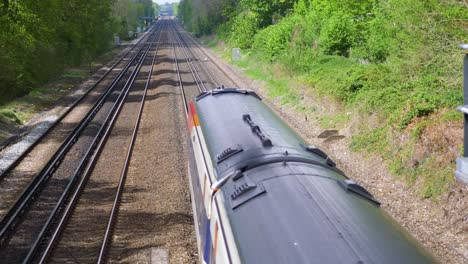 Three-carriage-South-Western-Train-travelling-on-railway-under-bridge,-slow-motion
