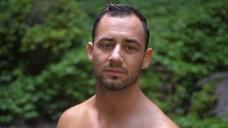 A-young,-attractive-man-with-a-serious-facial-expression,-looking-into-the-camera-and-around-his-surroundings-in-the-lush,-green-jungle-of-Bali