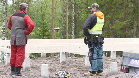 Toma-Manual-De-Un-Trabajador-Hablando-Y-Planificando-El-Trabajo,-Mientras-Construye-Los-Cimientos-De-Una-Casa,-En-Ostrobotnia,-Finlandia