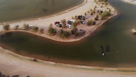 Aerial-view-from-drone-of-friends-having-a-picnic-near-Al-Qudra-lakes-in-Dubai-desert,-United-Arab-Emirates