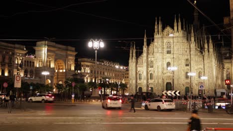 Night-timelapse-of-duomo-di-milano-with-people-and-traffic-in-foreground,-still-shot-with-motion-blur