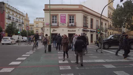Slowmo,-People-Crossing-the-Street-at-Crosswalk-in-Downtown-Seville,-Pan-Left