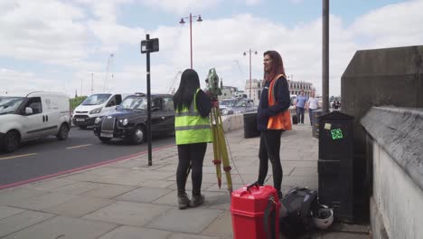 Dos-Agrimensores-Hablando-Durante-El-Trabajo,-Atasco-De-Tráfico-En-El-Fondo,-Ciudad-De-Londres