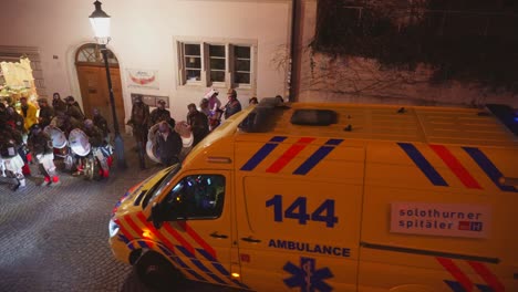 Ambulancia-Conduciendo-A-Través-De-La-Multitud-Durante-El-Festival-De-Carnaval-Al-Aire-Libre-Por-La-Noche
