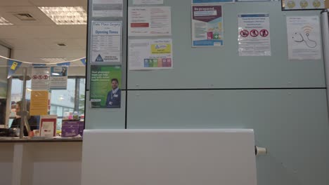 Hospital-notice-board---medical-reception-staff-working-at-computer-waiting-room