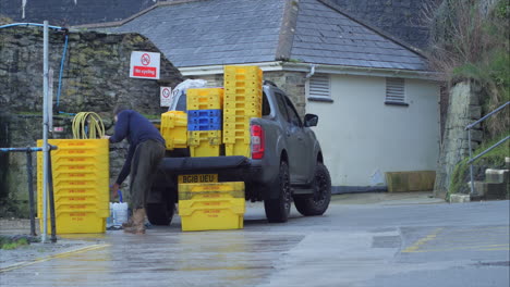 Man-loading-pickup-truck-with-fish-boxes-at-Mevagissey-Harbour-in-St-Austell