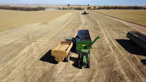 Tractor-trailer-pulling-beside-a-larger-trailer-to-offload-freshly-harvested-corn-to-take-to-the-grainary---aerial-view