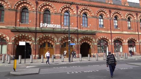 People-wearing-face-masks-walk-past-the-front-of-Kings-Cross-Station-St-Pancras-Station,-London,-UK