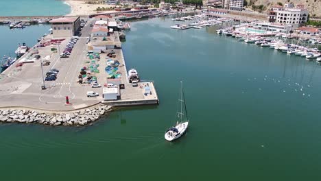 Descending-aerial-following-sailing-boat-over-water-in-the-harbour