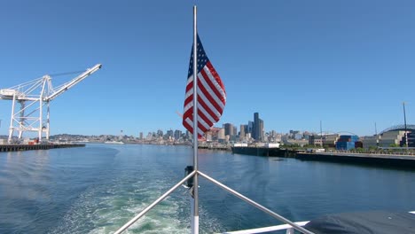 Parte-Trasera-Del-Velero-Con-Bandera-Americana-Y-Vistas-Panorámicas-De-Seatlle-En-Segundo-Plano.