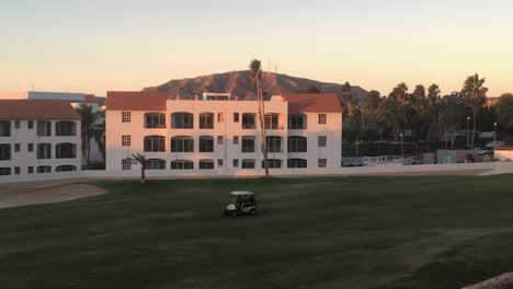 Zwei-Männer-Fahren-Während-Des-Sonnenaufgangs-In-San-Jose-Del-Cabo,-Mexiko,-Mit-Einem-Golfwagen-über-Einen-Golfplatz