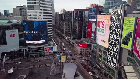 Yonge-Dundas-Square-and-Eaton-Centre,-Toronto-Canada,-Drone-Dolly-Out-past-Tall-City-Buildings