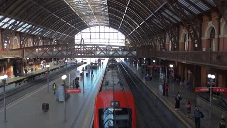 train-leaving-the-station,-while-passengers-wait-at-the-boarding-platform