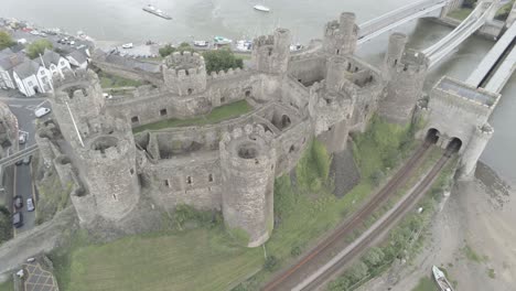 Medieval-landmark-historic-Conwy-castle-aerial-view-above-Welsh-seaside-landscape-wide-orbit-left