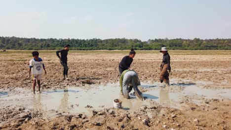 Familia-Buscando-Peces-En-Un-Campo-Fangoso