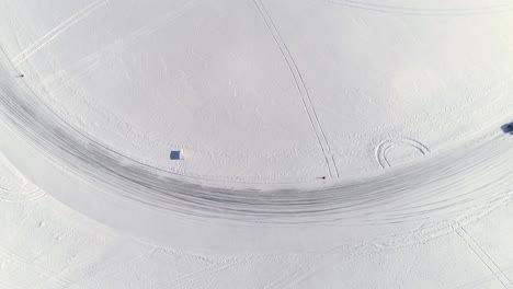Observed-from-high-above,-a-custom-built-utility-vehicle-drifts-around-an-icy-corner-on-a-frozen-race-track