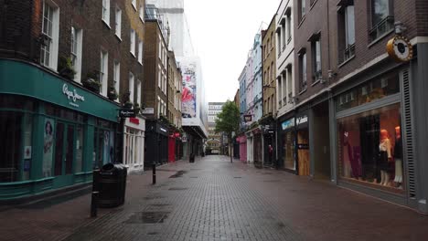 A-gimbal-shot-of-Carnaby-street-in-central-London-near-Oxford-circus-being-completely-dead-and-closed-on-a-Friday-afternoon-during-a-rainy,-moody-and-grey-day-during-the-lockdown-due-to-the-covid-19
