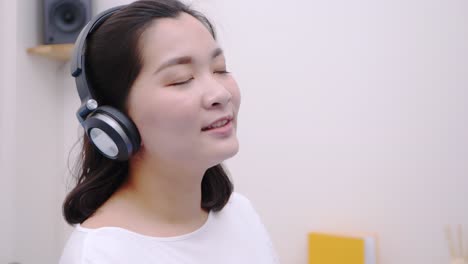 Asiatische-Teenager-Frau,-Die-Den-Bluetooth-Kopfhörer-Zum-Hören-Von-Streaming-Musik-Verwendet,-Liegt-So-Schön-Im-Bett